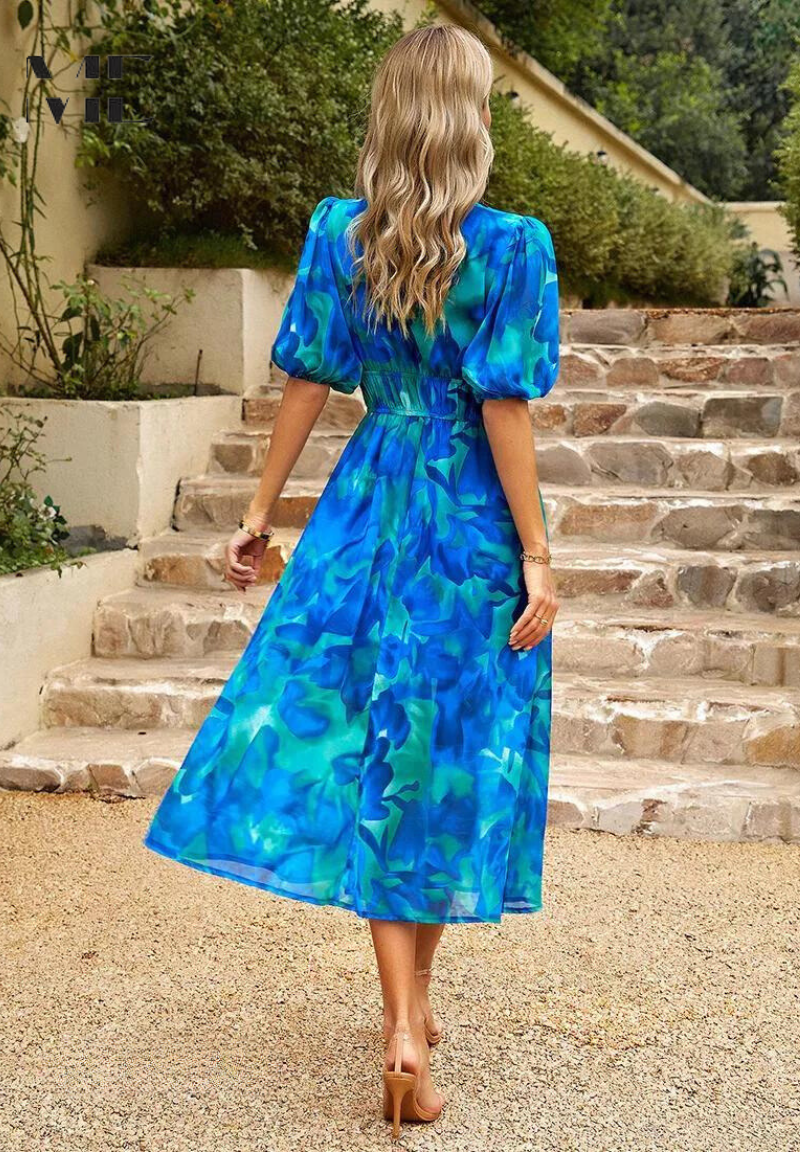 Woman model styling a feminine floral midi dress with an A-line skirt on a plain background, back view