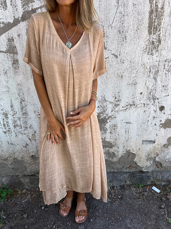 Woman model wearing a V-neck midi dress on a cement background.