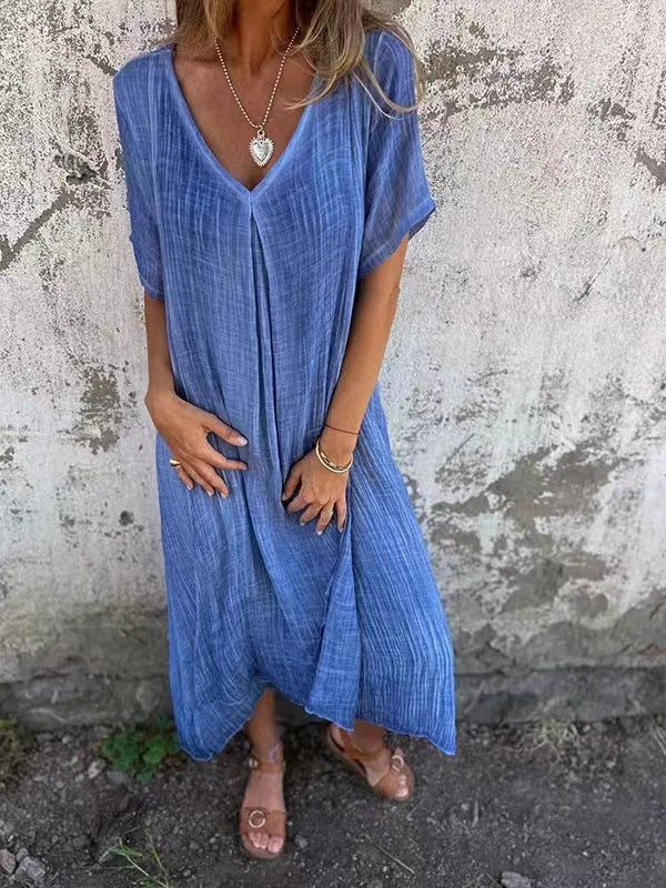 Model showcasing a relaxed fit short sleeve midi dress on a cement background.