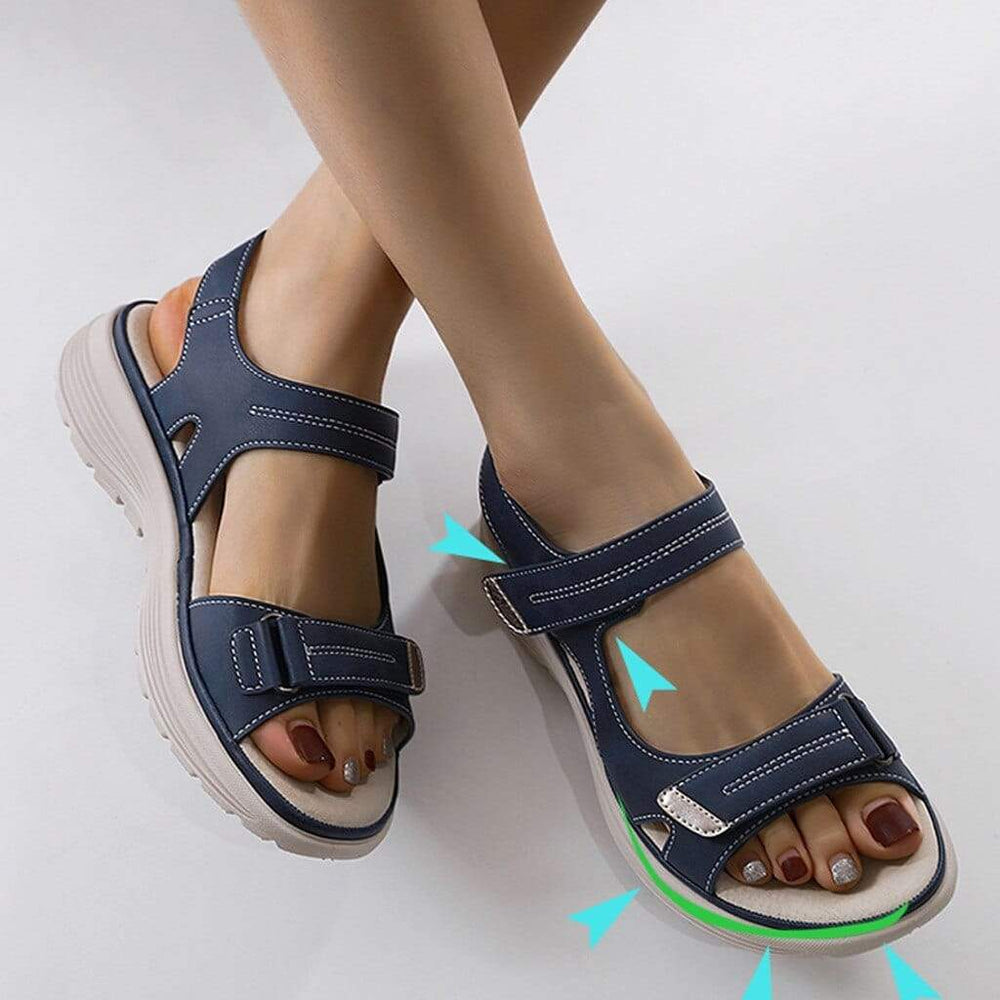 Woman standing in cushioned open-toe sandals against a plain background.