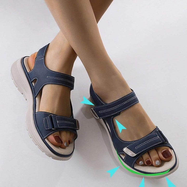 Woman standing in cushioned open-toe sandals against a plain background.
