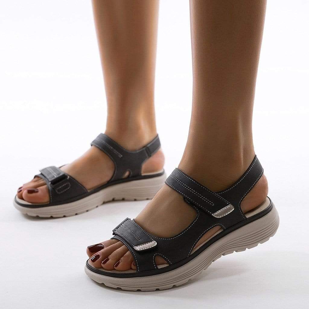 Female model wearing supportive walking sandals on a plain background.