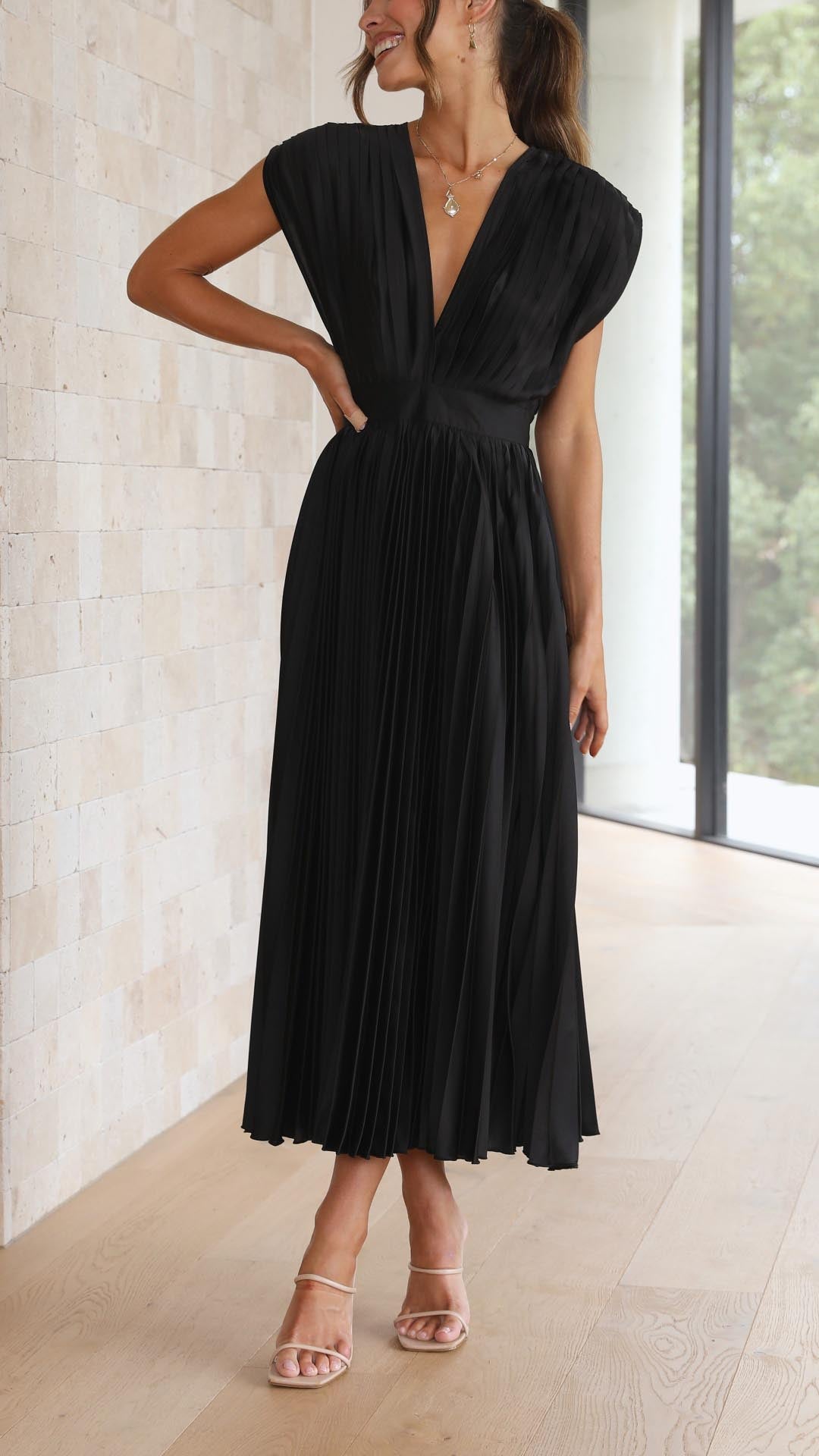 Woman showcasing a graceful V-neck midi dress with soft pleat details.
