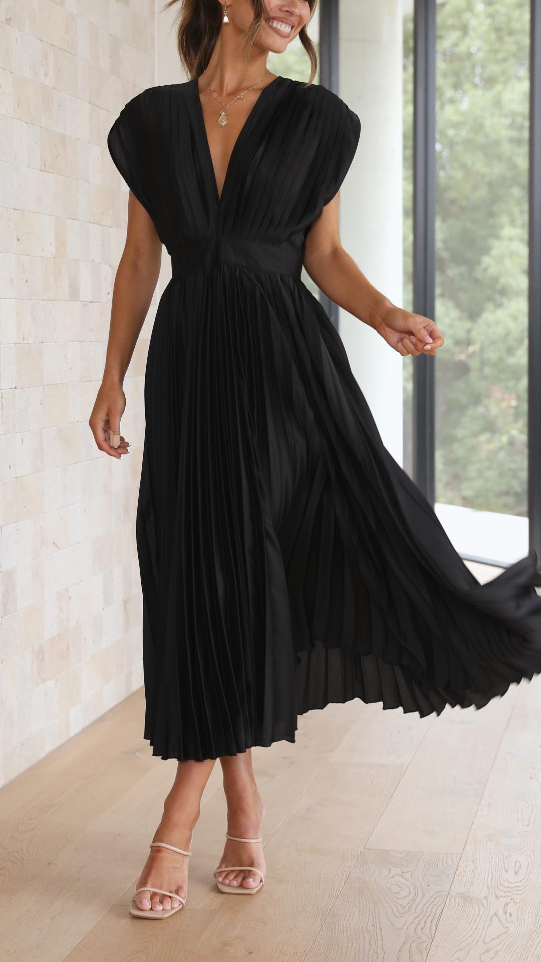 Female model in a flowing pleated dress designed for special events and celebrations.
