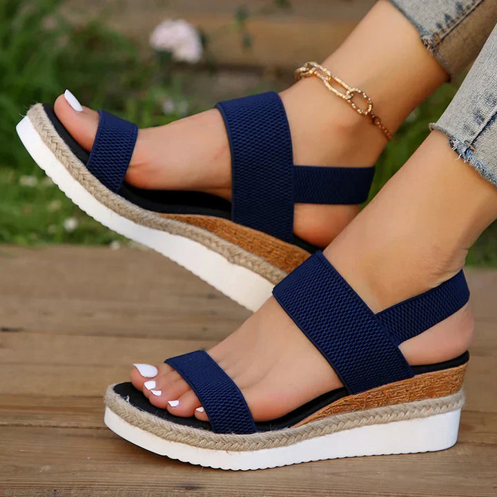 Foot model wearing feminine sandals in brown floor studio shot.